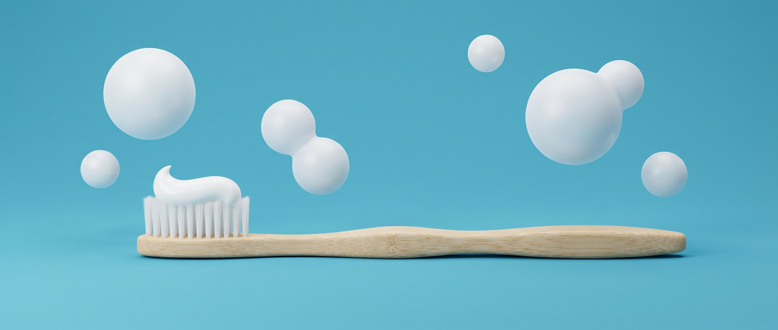 Bamboo toothbrush with a swirl of toothpaste and soft floating bubbles on a mid-blue background
