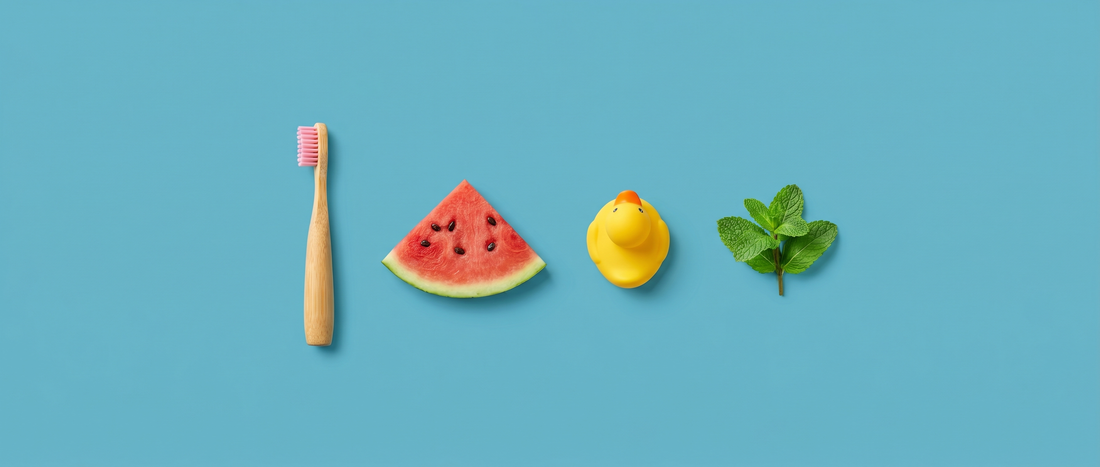 Kids bamboo toothbrush, watermelon slice, rubber duck and fresh mint on a mid-blue background