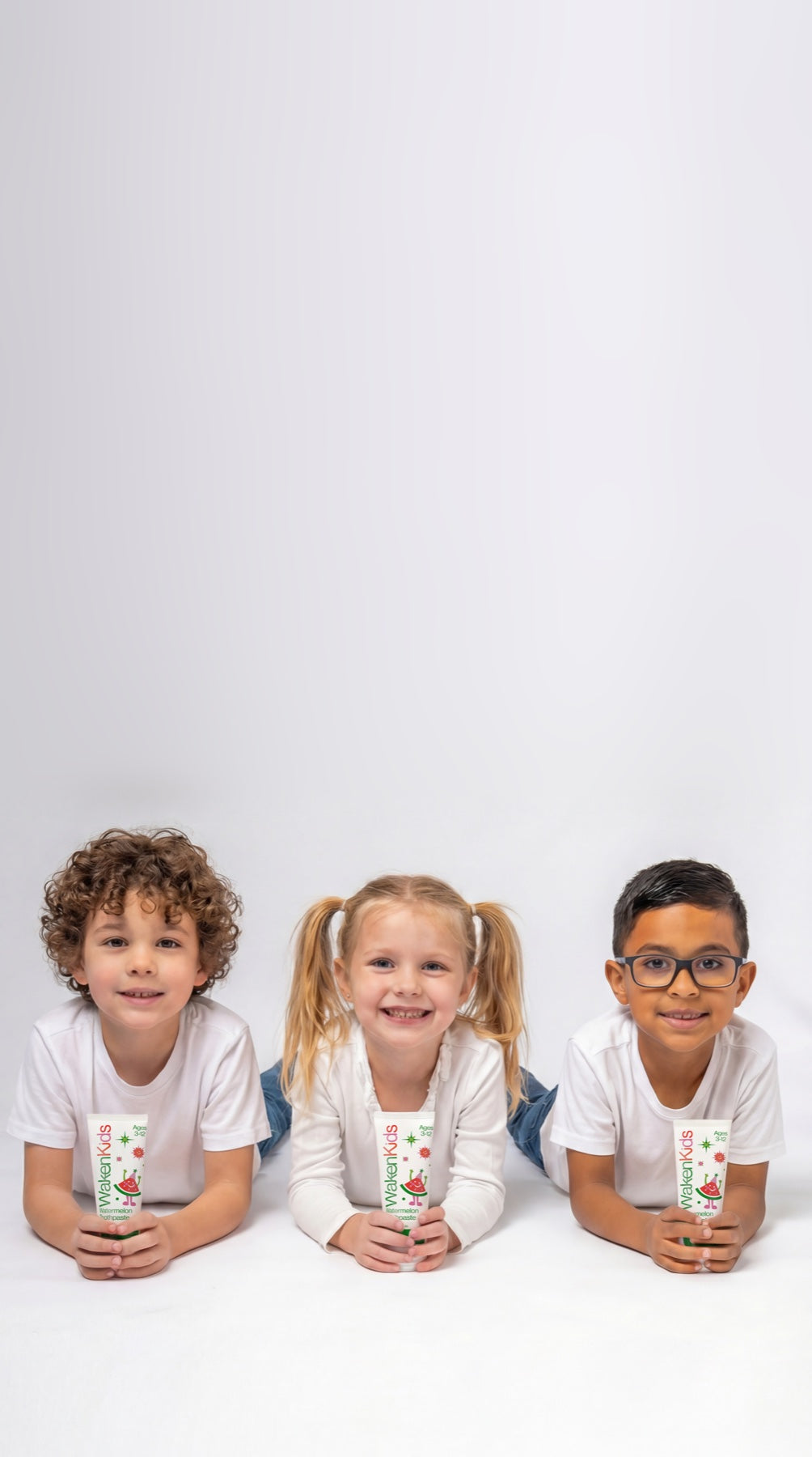 Three children holding Waken Kids toothpaste