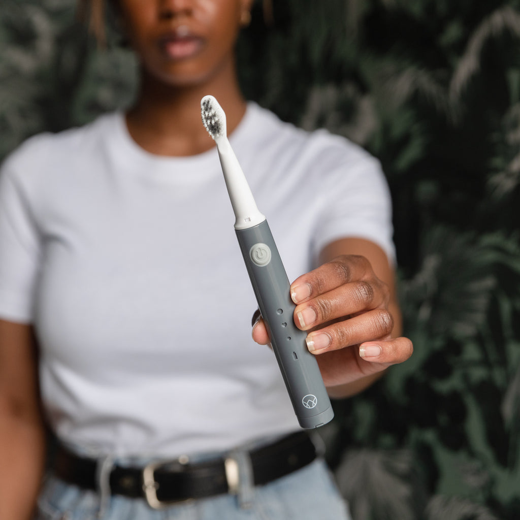 Woman holding the Waken Sonic Toothbrush in graphite grey